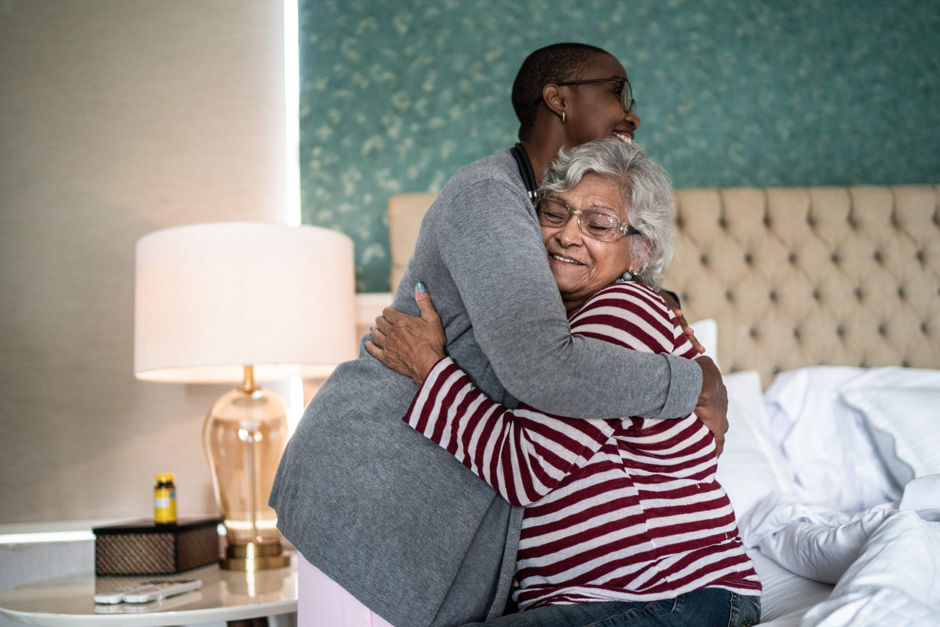 Nurse and senior woman embracing at home