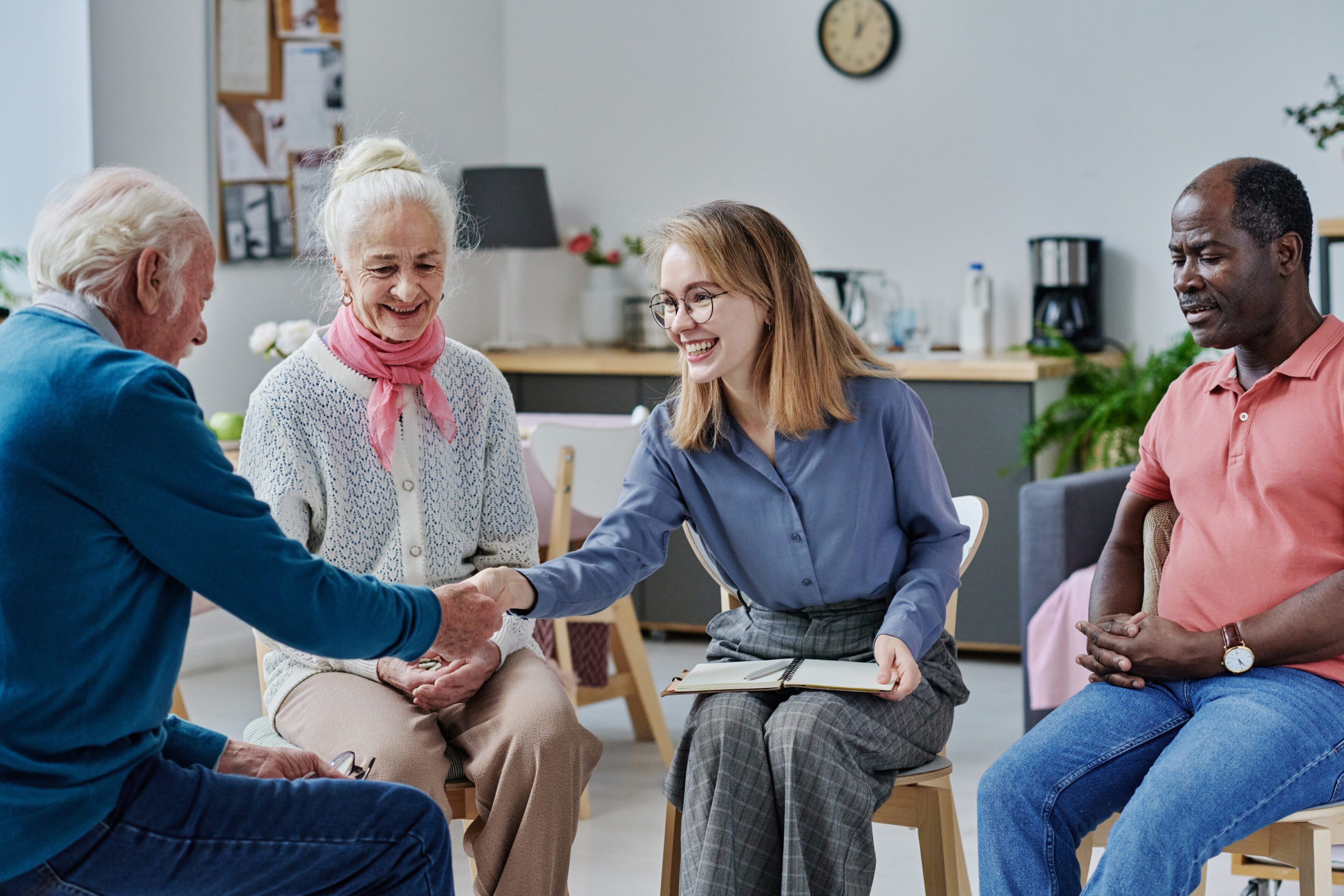 Young smiling psychotherapist greeting senior people during their session