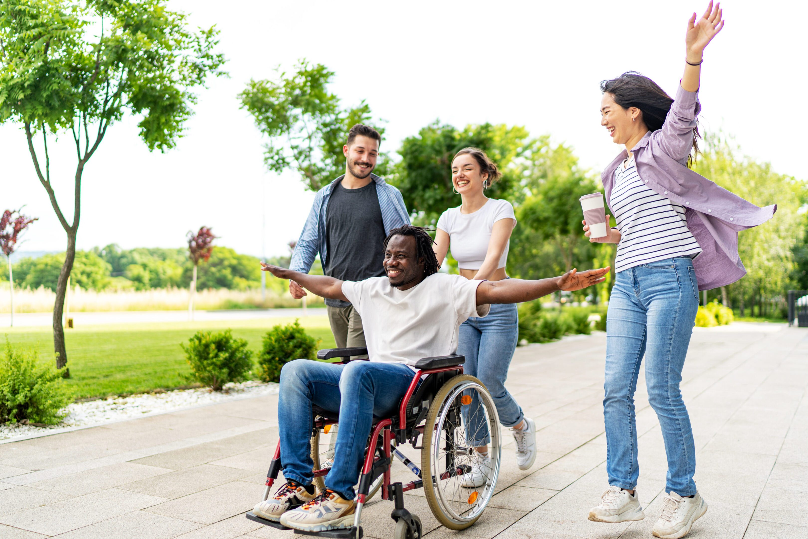 Friends having fun with young man in wheelchair on street